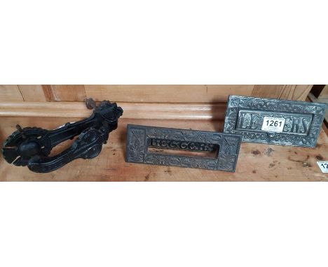 A Victorian cast metal letter box slot for a door, aperture 13.75cms; another similar and a decorative cast metal door knocke