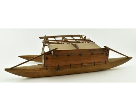 A vintage 20th century Polynesian outrigger double canoe, carved from hardwood. The boat with raised surface over twin keels.