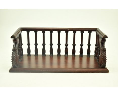 A 19th century inspired carved mahogany desktop book trough. The trough featuring a banister top over turned finials with aca