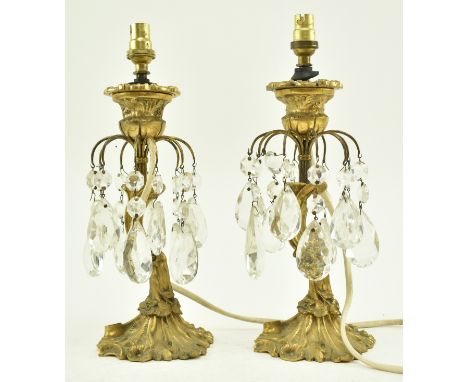 A pair of early 20th century French patinated bronze table lamps. Each lamp cast gilt foliate form with faceted glass tear sh