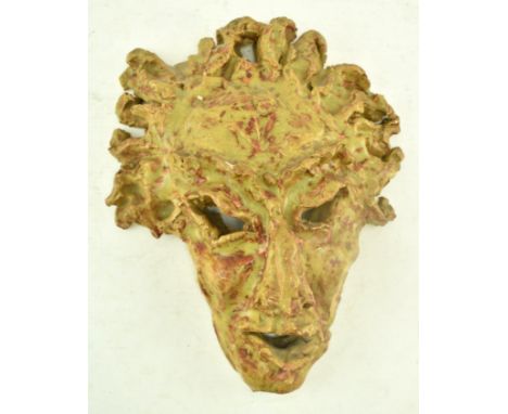 A vintage studio art pottery Brutalist inspired glazed ceramic figurative mask. The mask depicting a Green Man style face wit
