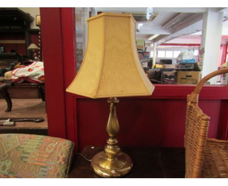 A brass table lamp with peach shade