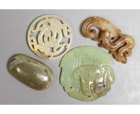 Four Chinese jade carvings, to include a face plaque, a dragon plaque, disc and a pebble carving, largest 6.5cm long, (4)