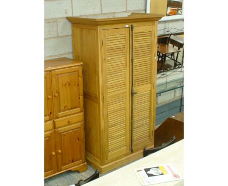 A Light oak French style wardrobe with two louvre doors raised on a plinth base.