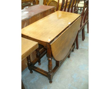 An 18th Century oval oak drop leaf dining table on ring turned baluster supports.