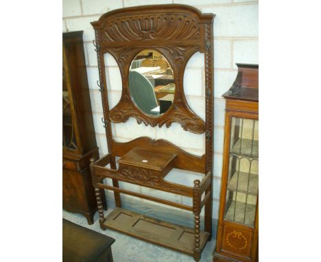 A Late Victorian carved oak hall stand
The scrolling leaf carved back centred with an oval mirror above a hinged glove box an
