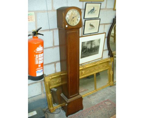 An Early 20th Century oak cased granddaughter clock with a silvered dial 