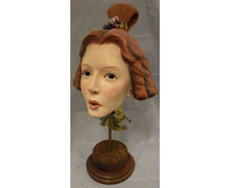 A 20th Century musical "box" automaton as a woman's head, her hair in ringlets, on a pedestal to wooden socle base   CONDITIO