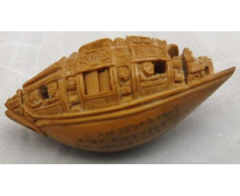 A late 19th Century carved coquilla nut boat finely decorated with moveable shutters and figures, the hull with eight line in