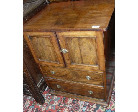 A Georgian mahogany converted commode, the rectangular top with rounded corners above two panelled cupboard doors with flamed