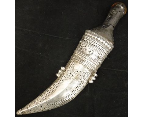 A 19th Century Jambiya dagger with remnants of rhinoceros horn handle, the curved blade housed in a pierced and engraved whit