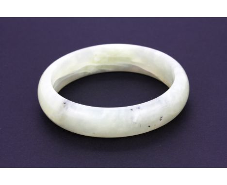 A Chinese pale celadon green nephrite jade bangle, W. 14.8mm internal Dia. 5.7cm.