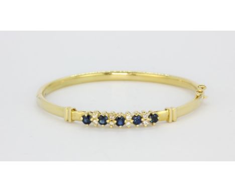 An 18ct yellow gold sapphire and diamond set bangle, L. 6.5cm.