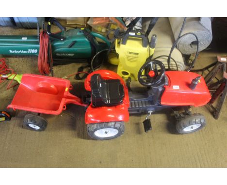 A child's red coloured pedal tractor and trailer unit