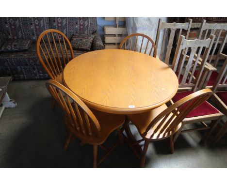 A modern light oak circular table and set of four stick back chairs