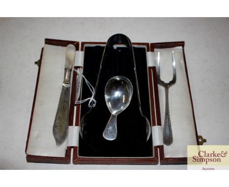 A Georgian silver caddy spoon; a pair of plated sugar tongs; a plated butter knife with mother of pearl handle; and a plated 