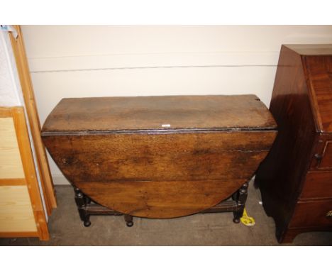 An antique oak gate leg dining table fitted single drawer with rounded drop leaves