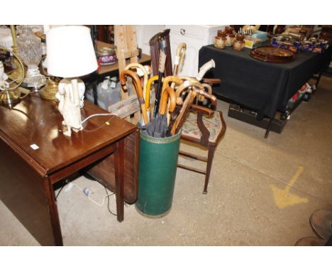 A leatherette covered stick stand and contents of various walking sticks, umbrellas etc.