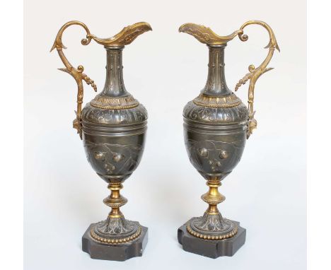 A Pair of Parcel Gilt Bronze Ewers, 19th century, of neo-classical style, decorated with stylized flowers and on slate plinth