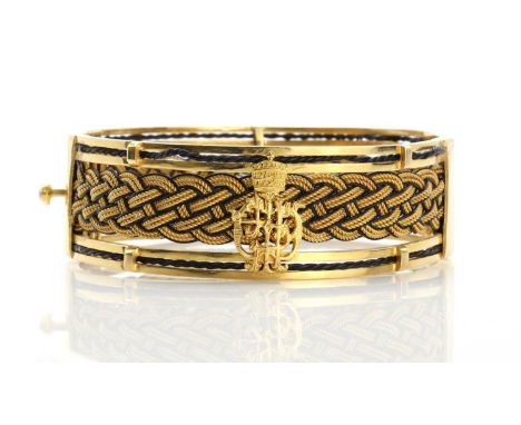 An Ethiopian high carat gold elephant hair hinged bangle,gifted by Haile Selassie. A flat section hinged bangle with a centra