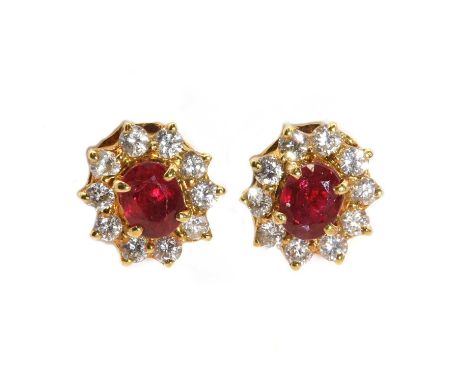 A pair of Continental ruby and diamond oval cluster earrings,with an oval mixed cut ruby, four claw set to the centre. A bord