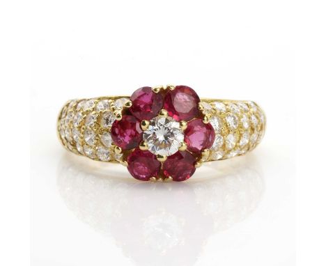 An 18ct gold ruby and diamond cluster ring, with a brilliant cut diamond, claw set to the centre. A surround of six circular 