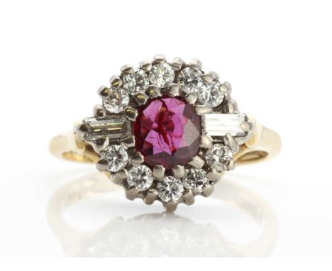 An 18ct gold ruby and diamond cluster ring,an oval mixed cut ruby, claw set to the centre, flanked by a baguette diamond on e