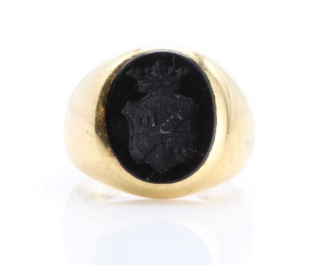 A gentlemen's gold and onyx set oval signet ring, possibly Swiss. The oval flat section onyx tablet, intaglio engraved with a