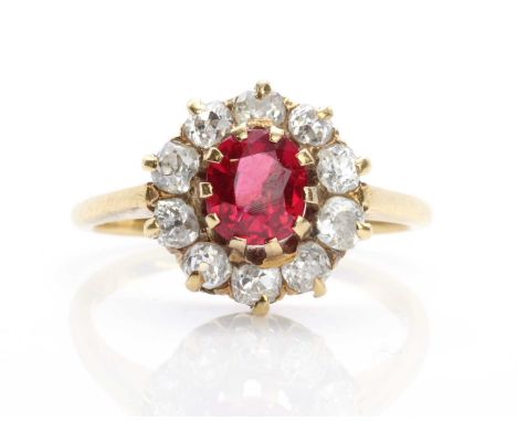 An Edwardian synthetic ruby and diamond cluster ring, with an oval mixed cut synthetic ruby claw set to the centre. A border 
