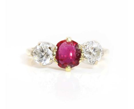 An 18ct gold ruby and diamond three stone ring,with a central oval mixed cut ruby, claw set in a yellow collet. An old Europe