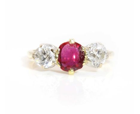 An 18ct gold ruby and diamond three stone ring,with a central oval mixed cut ruby, claw set in a yellow collet. An old Europe