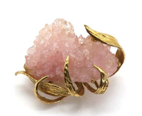A druzy rose quartz brooch, c.1970,with a freeform rose quartz specimen, claw set with long leaves, with a molten textured fi