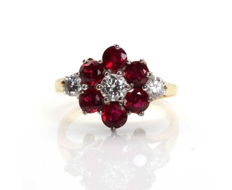 A diamond and ruby cluster ring,with a brilliant cut diamond, claw set to the centre. A border of circular mixed cut rubies, 