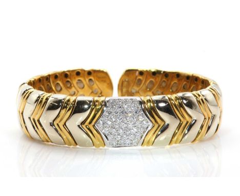 An Italian two colour gold diamond set sprung bangle, with a central white panel, pavé set with graduated brilliant cut diamo
