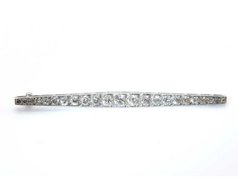 An Art Deco diamond bar brooch,graduated old cut diamonds, grain set, to a tapered white gold bar faced in platinum, with a c