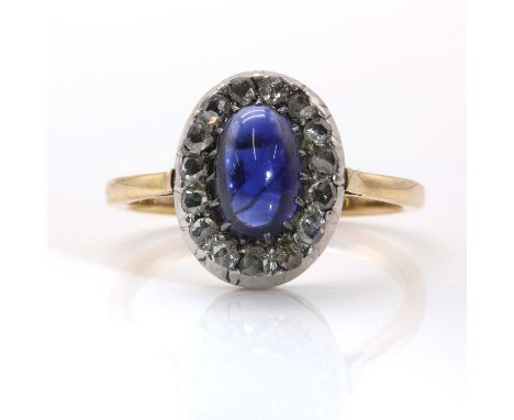 A sapphire and diamond oval cluster ring,with an oval cabochon sapphire, claw set to a border of rose cut diamonds, all in cu