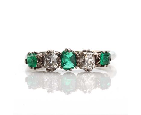 A graduated five stone emerald and diamond ring,with a cushion shaped step cut emerald, claw set to the centre. A cushion cut