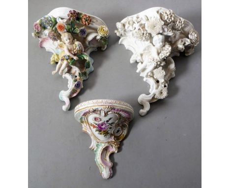Two late 19th century porcelain wall brackets in high Rococo style; one decorated, the other single glazed. Both with winged 