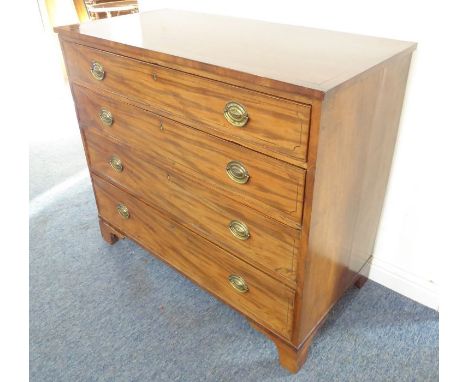 An early 19th century mahogany crossbanded chest; four full-width graduated strung drawers with replaced, stamped brass ovals