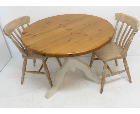 A modern circular pine kitchen-style table with cream-painted tripod base in shabby chic style, together with a pair of limed