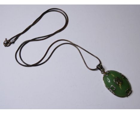 A Chinese silver and celadon jade mounted oval pendant, central conforming character mark within four mounts terminating in h