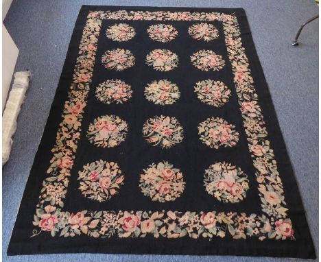 An Aubusson needlepoint tapestry; black background with 15 circular floral medallions surrounded by similar border, lined (26