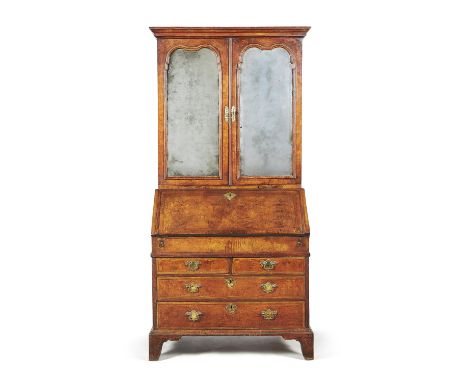 A George I walnut and feather banded bureau bookcase, circa 1720, the shaped mirror panel doors opening to an adjustable shel