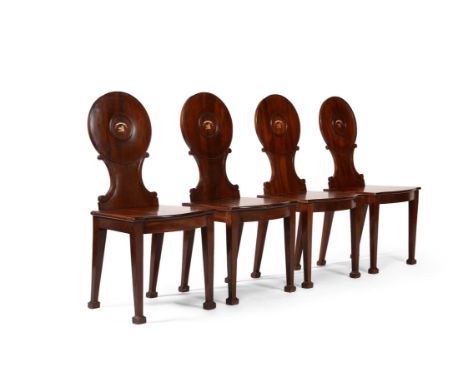 A set of four George III mahogany hall chairs, circa 1790, each back centred by a painted armorial reading 'NIL TIBI' above a