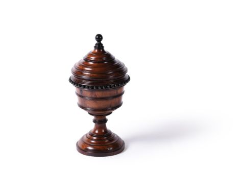 A turned yew and ebonised urn and cover, English or Dutch, 19th century, the elaborately rib moulded cover mounted with a sph