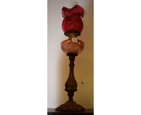 A Victorian style oil lamp, pink reservoir, cranberry glass shade, gilt metal baluster column, cast foot