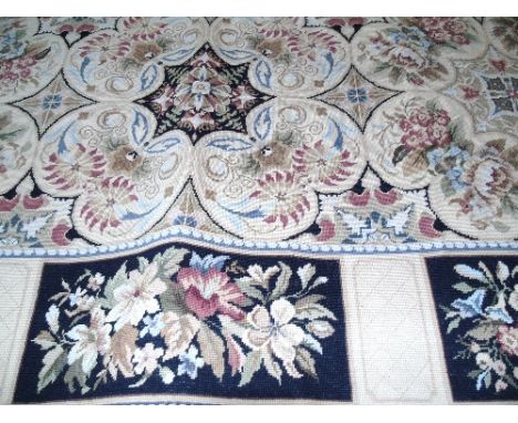An Aubusson Type Needlepoint Carpet with stylised floral medallions and running borders, on a beige ground.