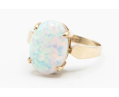 A 9CT YELLOW GOLD AND OPAL RING, the oval cut opal claw set simply in an open mount between solid tapering shoulders on a pla