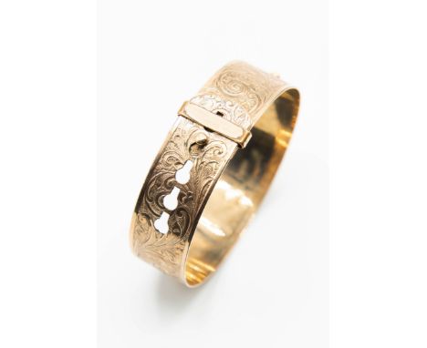 A 9CT YELLOW GOLD BACK AND FRONT BANGLE BY HENRY GRIFFITHS &amp; SONS, the buckle design bangle with swirled floral engraving