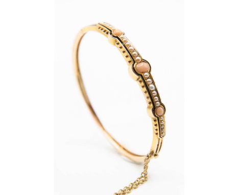 A LATE 19TH CENTURY CORAL AND SEED PEARL BANGLE, the cut out detail mount set to the centre with three polished coral beads a